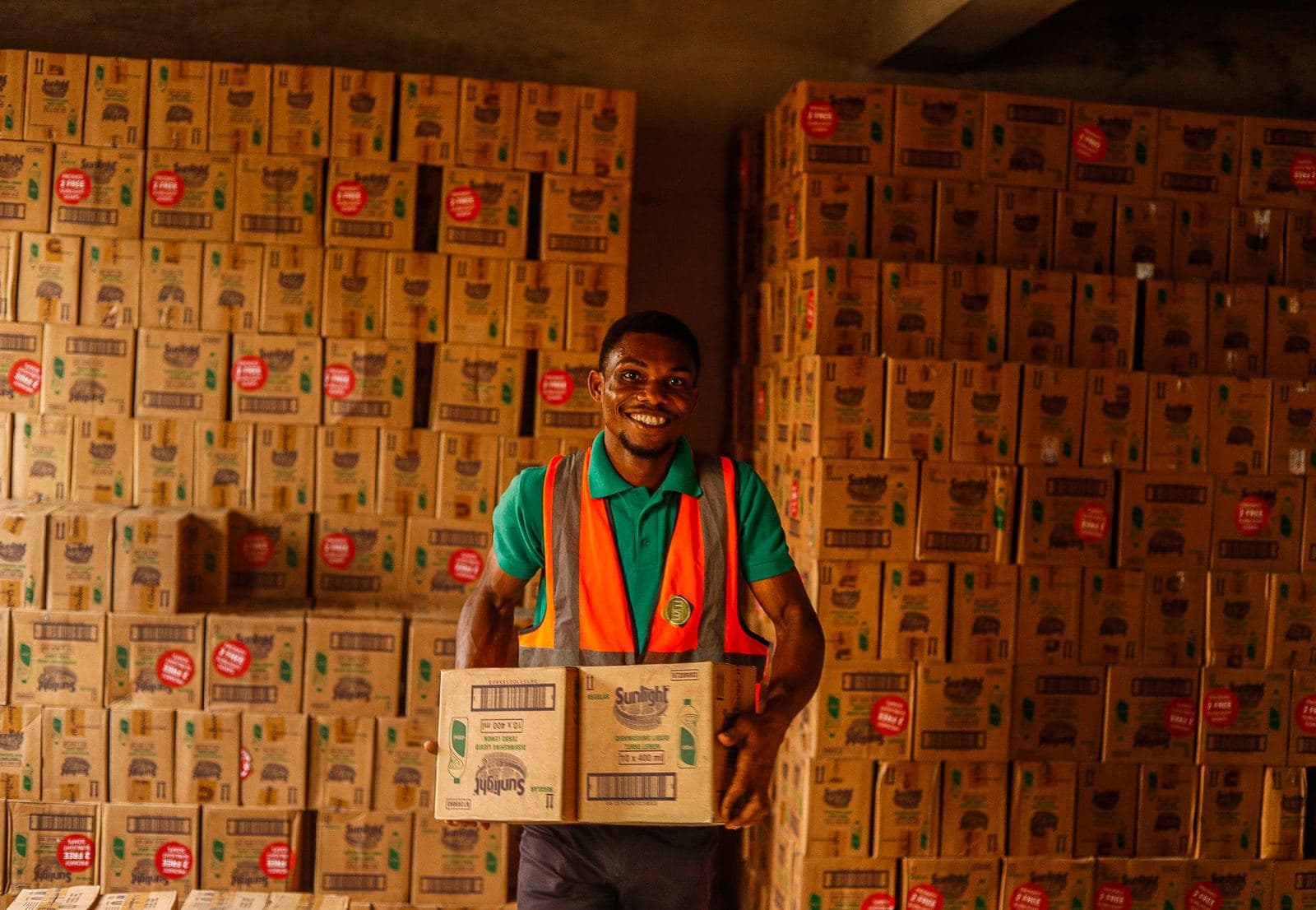 Magasinier souriant portant un carton dans un entrepôt
